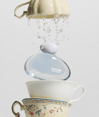 Glass fragrance bottle labeled with 'Future Society' being filled with water from a teacup.
